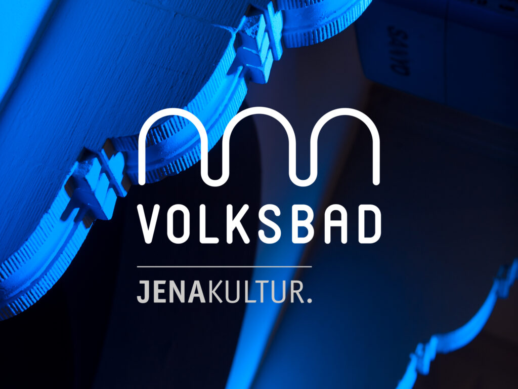 weiĂźes Volksbad-Logo liegt auf einem Foto, das dunkle Farben hat. Logo ist darauf gut zu erkennen.